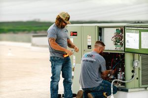 Two R2 technicians servicing a commercial rooftop HVAC unit